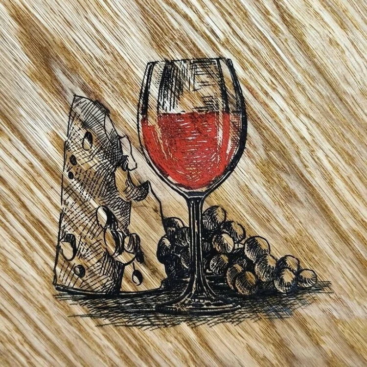 Wypalony zwór na desce do podawania przekąsek z kieliszkiem czerwonego wina, dużym kawałkiem sera i winogronami. Wymiary deski 35x27 cm.