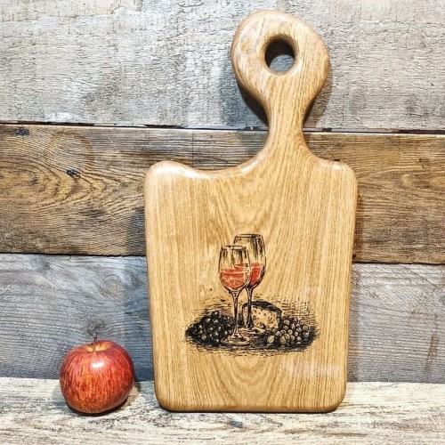 Ręcznie robiona drewniana deska  do serwowania z dębu. Deska jest  nieregularnym kształcie, deska posiada rączkę  i ozdobny grawer z kieliszkami wina, serem i winogronami  rozmiar deski 41x22cm