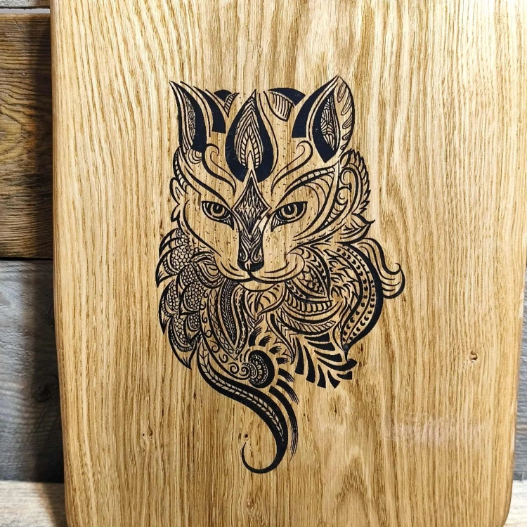 Grawer  kota na ręcznie robionej drewnianej desce  do podawania przekąsek. Deska jest wykonana z dębu. Deska jest  nieregularnym kształcie. Rozmiar deski 46x25cm