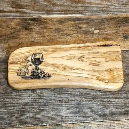 Deska do krojenia i serwowania przekąsek z drewna oliwnego po lewej stronie deski jest grawer z  kieliszkiem wina, winogronami i serem, wymiary deski 16x34x2,5cm