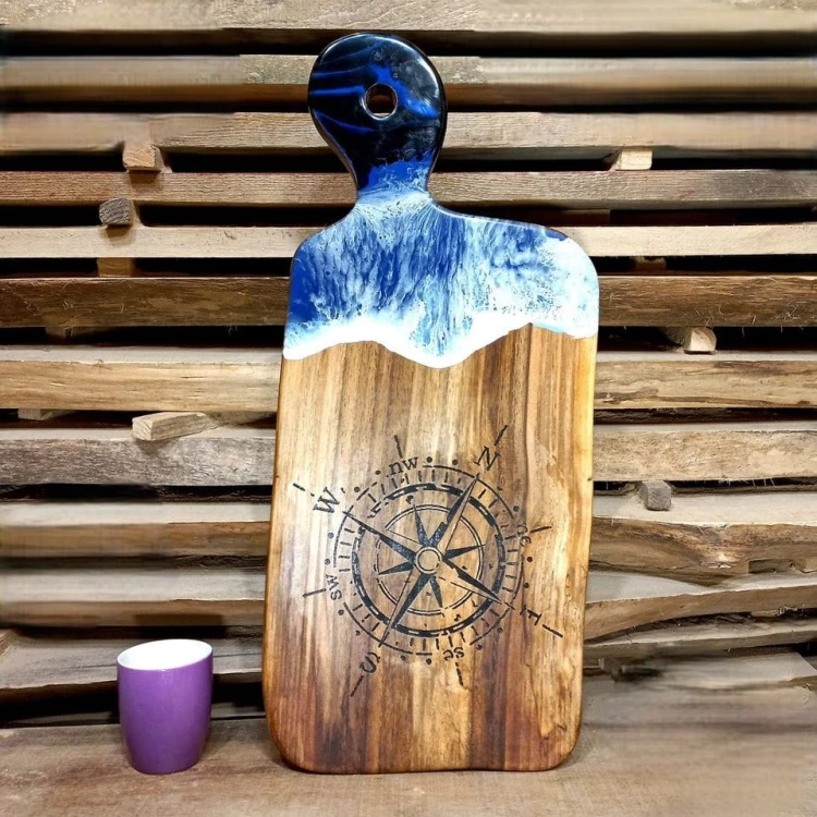 Deska do serwowania z orzecha włoskiego z żywicą imitująca fale morskie
na desce jest wypalony kompas
deska ma rączkę z dziurką 
wymiary deski 62x28cm