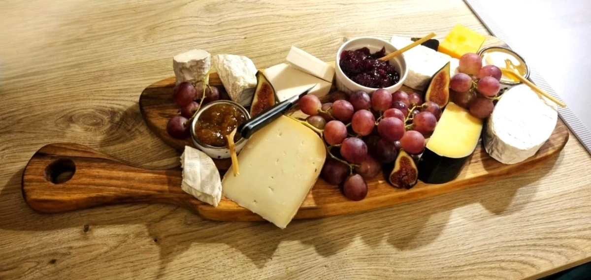 ręcznie robiona deska do krojenia i podawania przekąsek z paroma radzajami sera,winogronami i figami