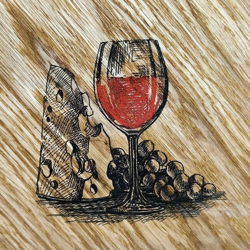 Zbliżenie na precyzyjny grawer kieliszka wina i fakturę dębowych słojów na desce 35x29cm